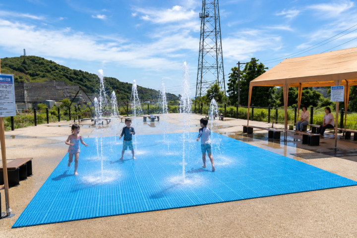 噴水広場で水しぶきと遊ぶ子どもたち