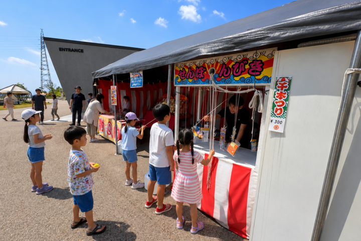 千本引きの屋台でひもを引く子どもたち