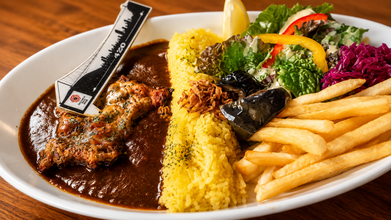 ダムカレー。ライスでダムを表現し、カレーソースとサラダ、ポテトを添えたプレート