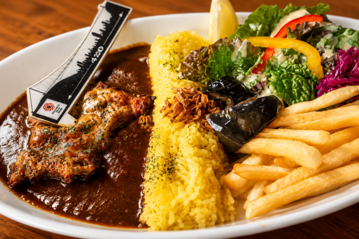 ダムカレー。ライスでダムを表現し、カレーソースとサラダ、ポテトを添えたプレート